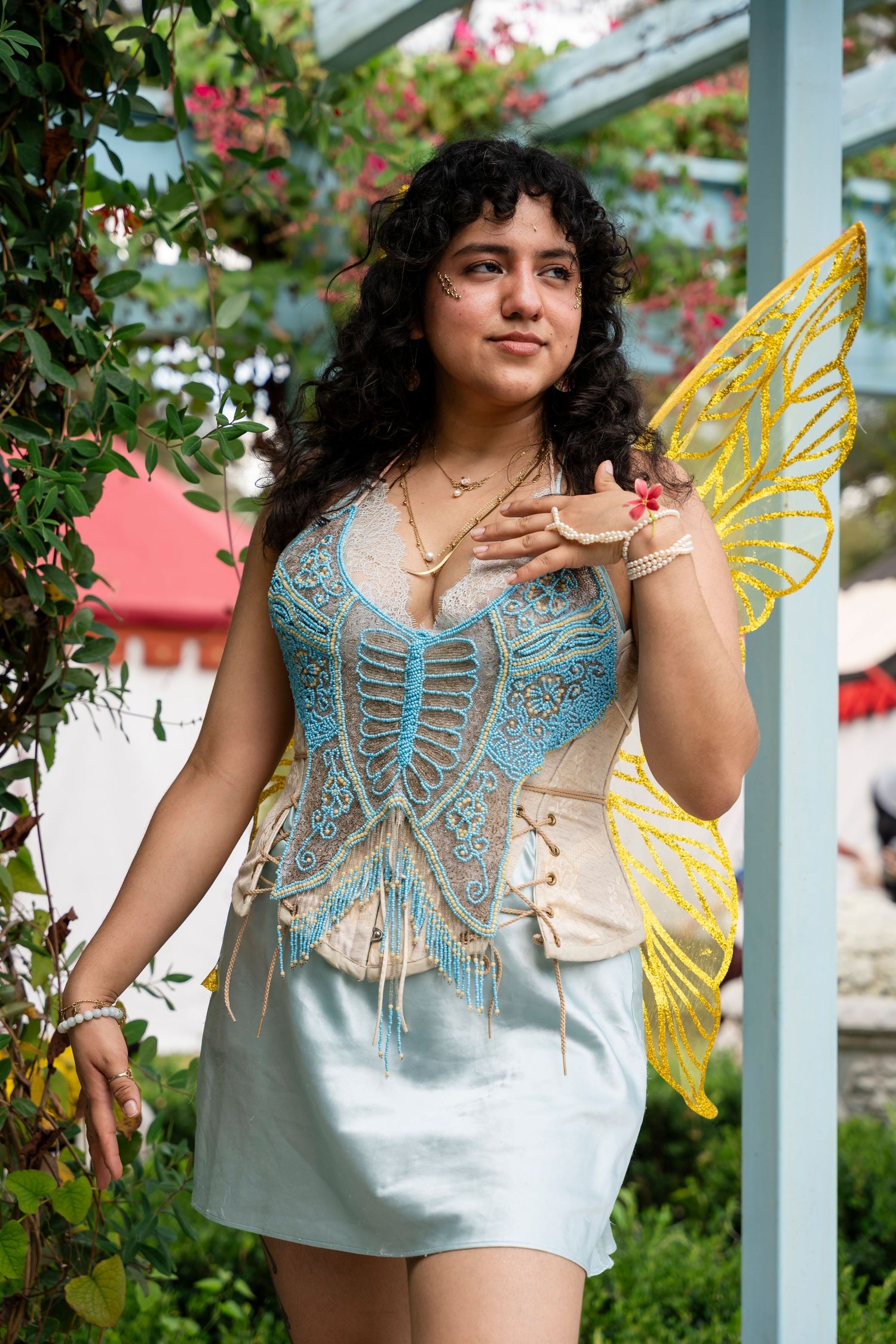 A series of photos showing a light blue crochet butterfly top with decorative yellow wings in a garden setting.