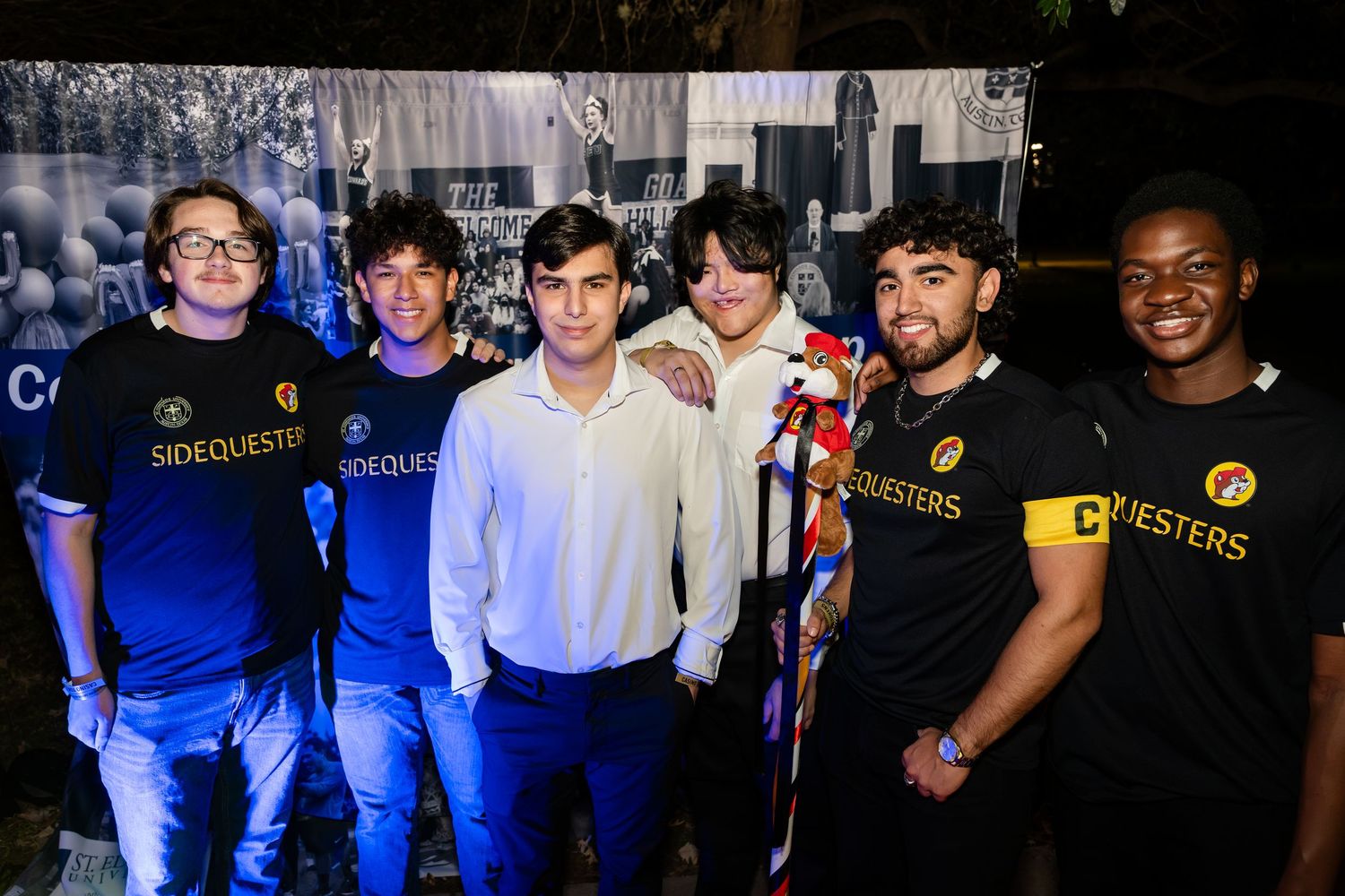 A group of people posing together at a social event wearing casual and formal attire.
