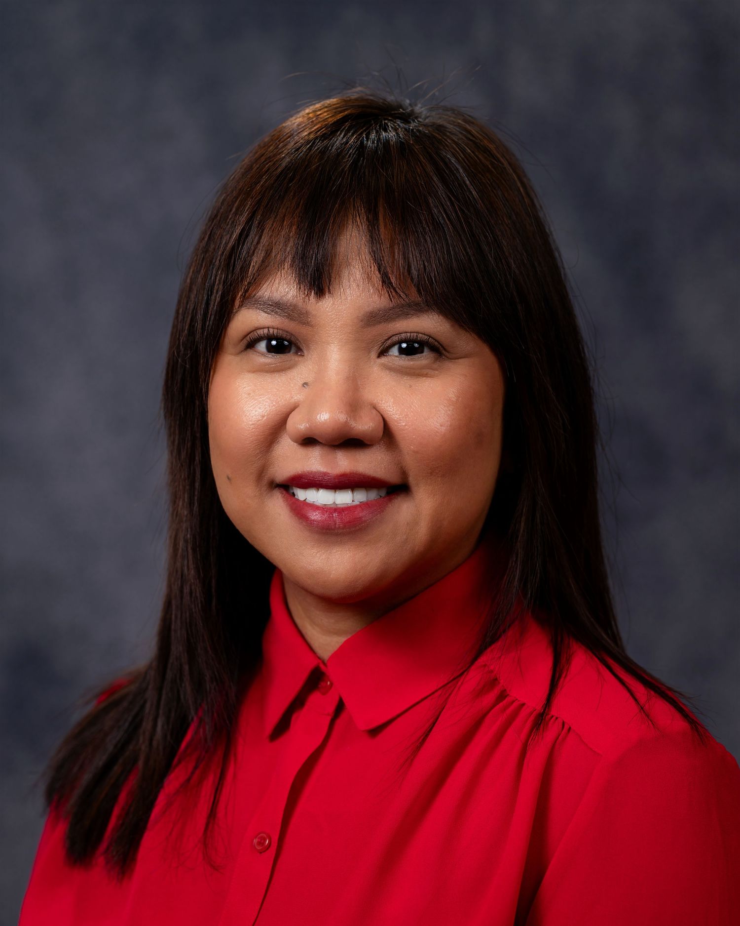 Professional headshot series of a person in a bright red collared top against a dark gray background.