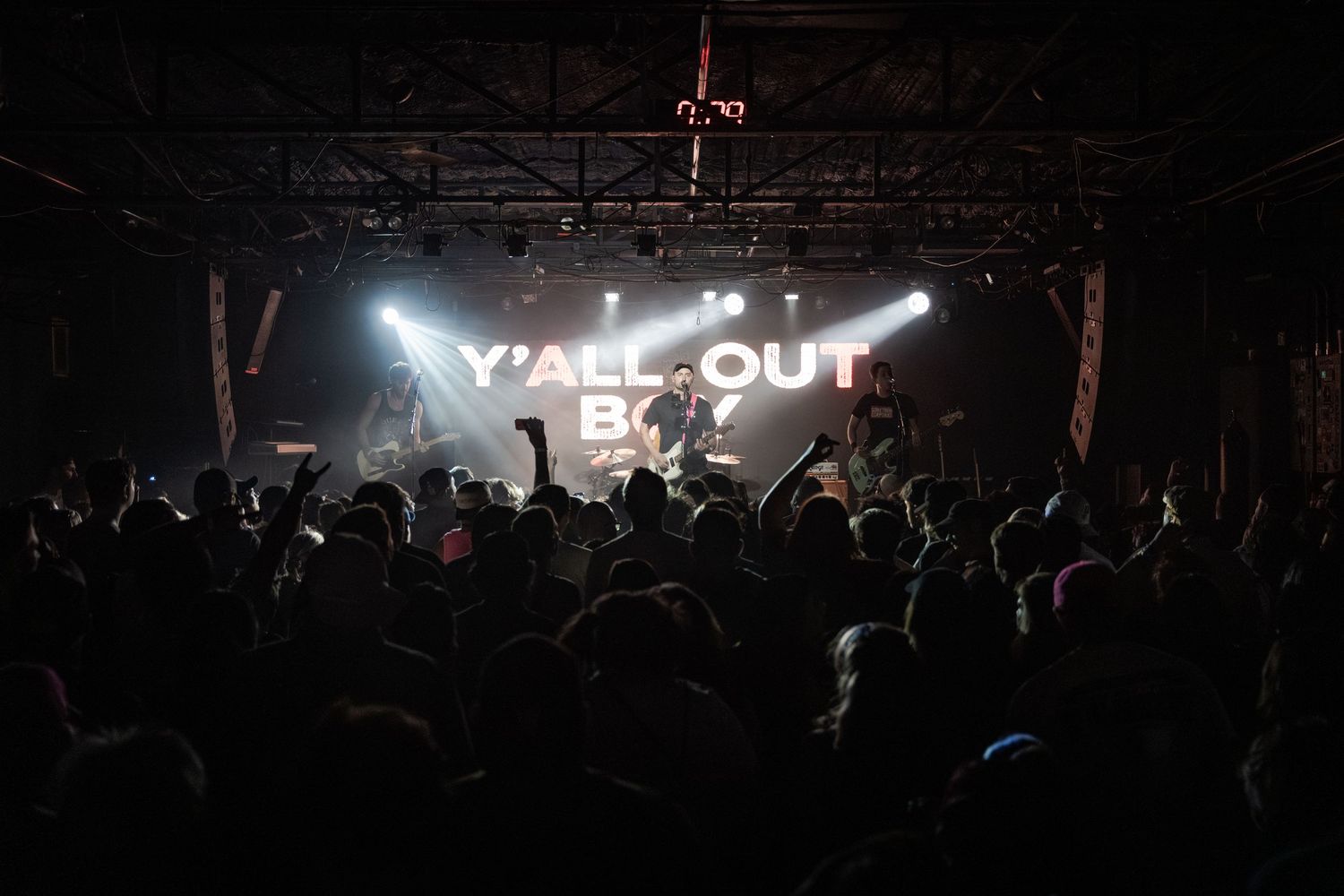 Fall Out Boy performing live on stage with dramatic lighting and an energetic crowd at a concert venue.