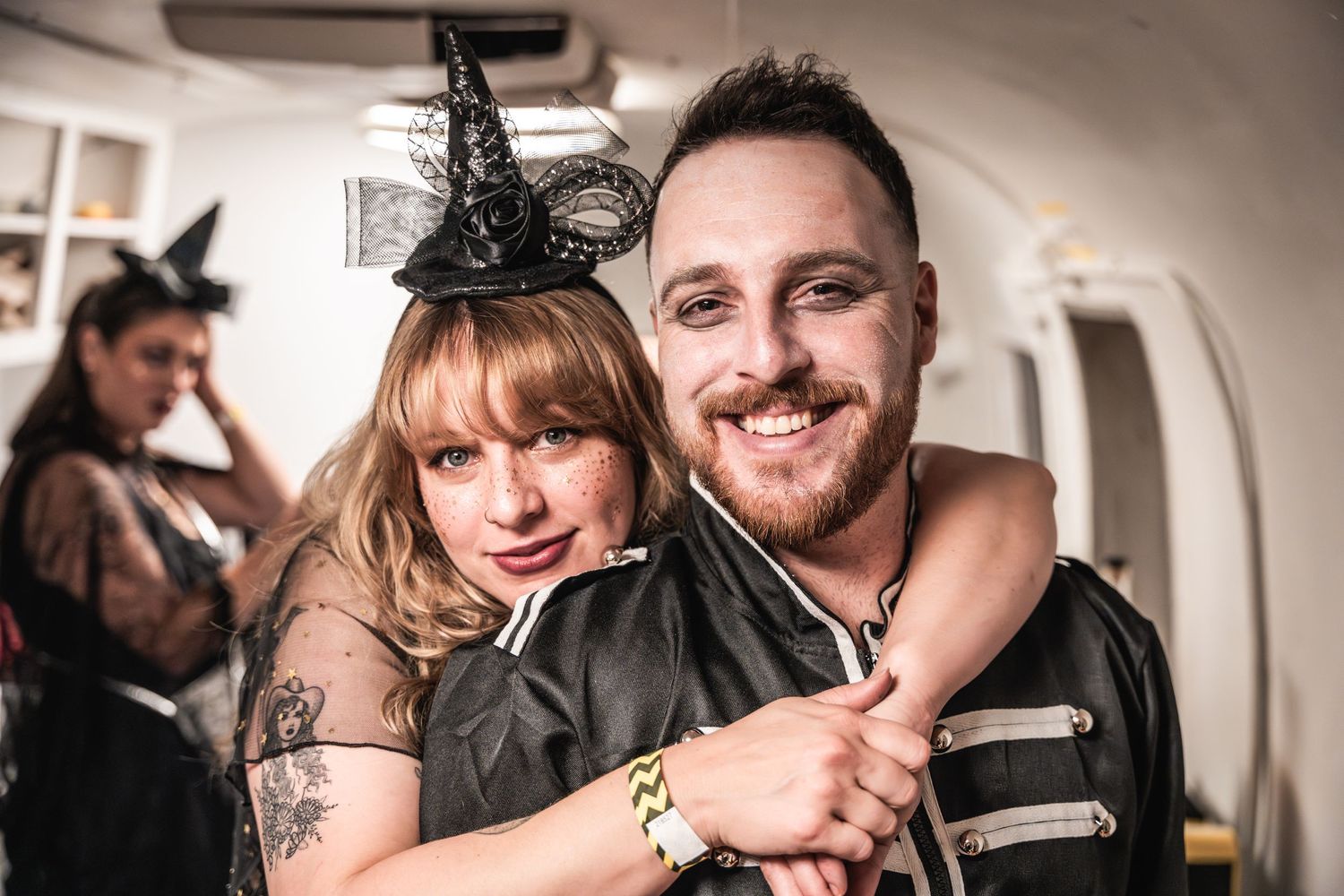 A couple in gothic Halloween attire embracing at what appears to be a party.