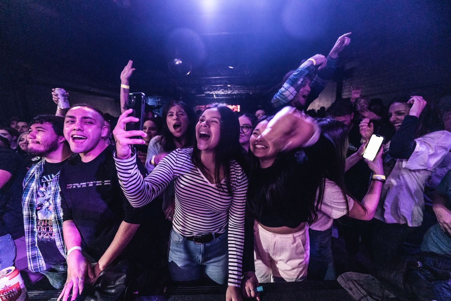 Concert attendees enjoy live music under purple lighting in an intimate venue.