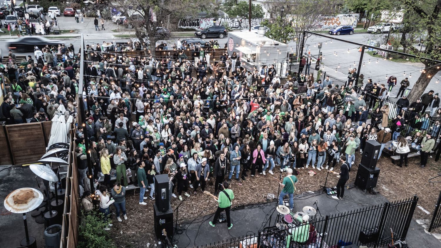 Aerial view of large crowd gathered at an outdoor venue with fencing and equipment visible.
