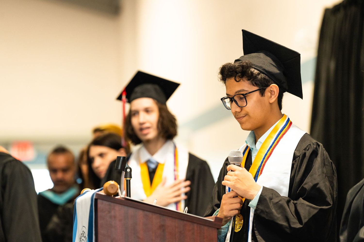 Graduation ceremony with graduates in caps and gowns holding diplomas.