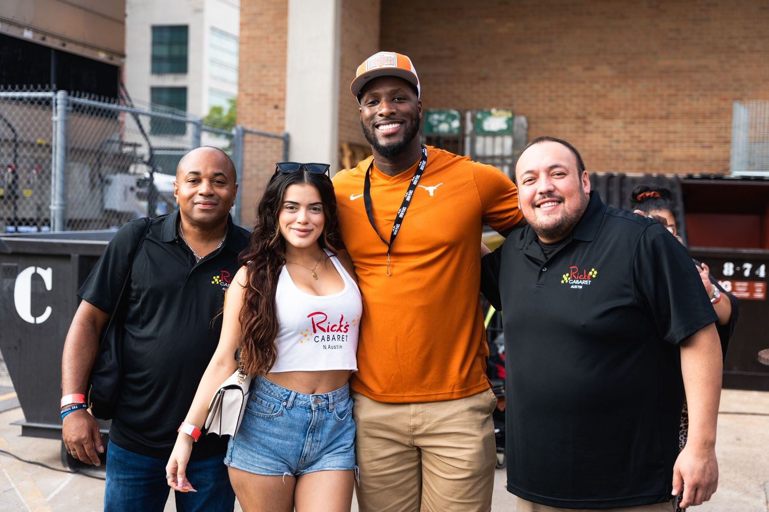 Group of four people posing together at outdoor event wearing casual attire.