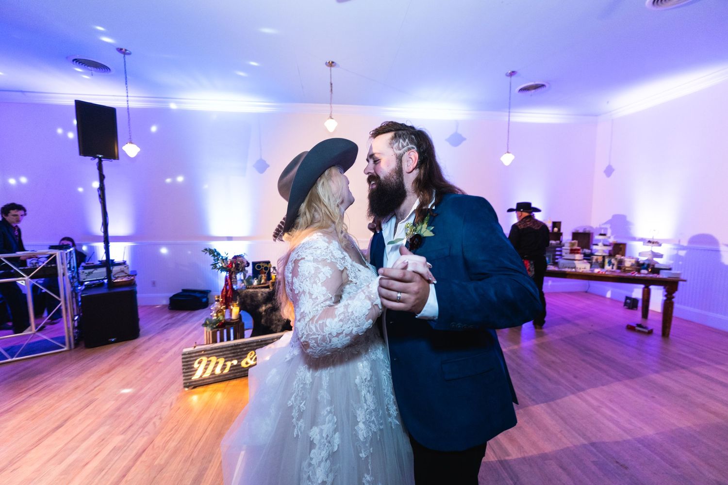 Couple shares an intimate first dance moment on a purple-lit dance floor at their wedding reception.