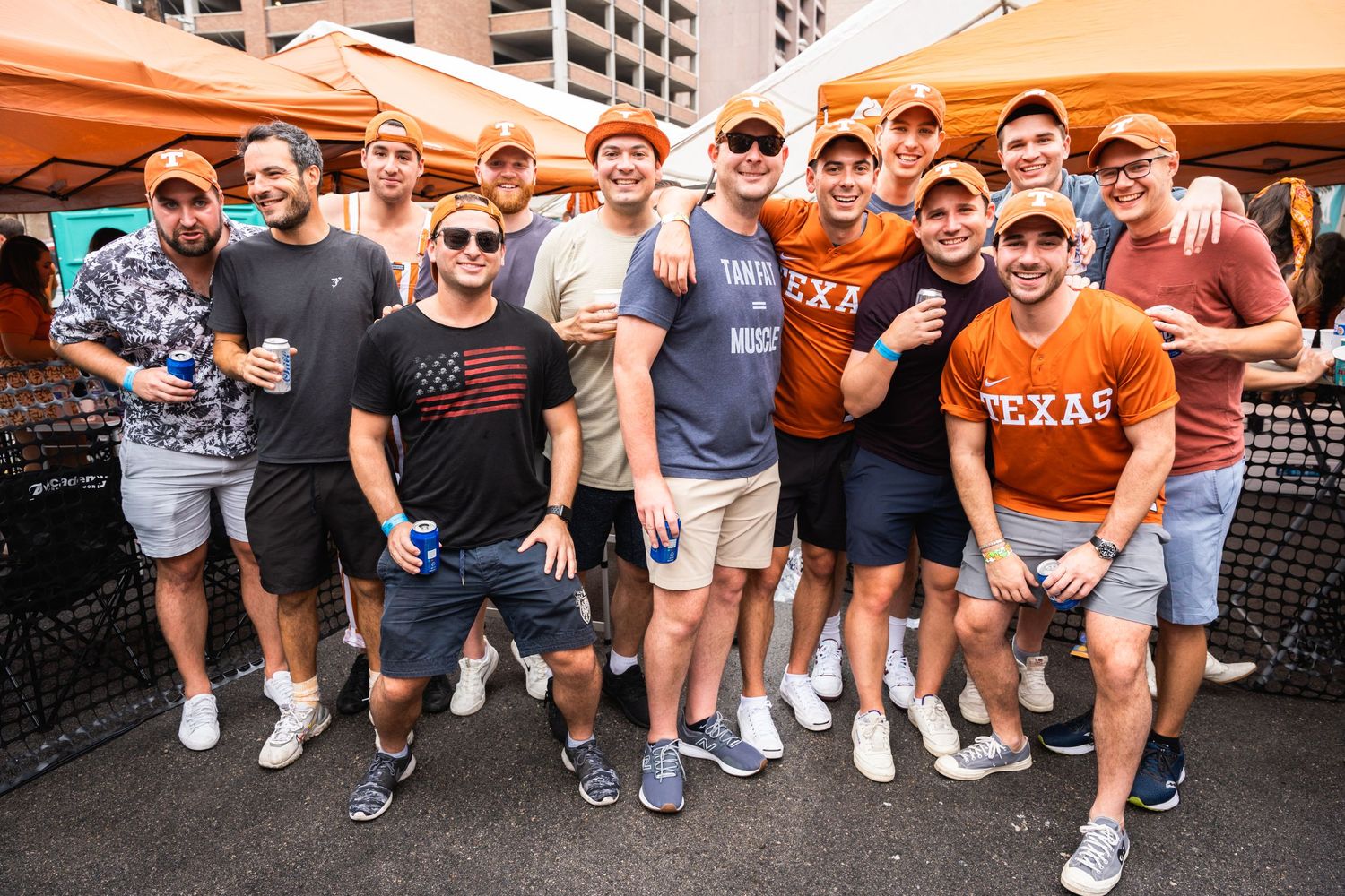 Large group of fans in casual attire and Texas gear posing together at an outdoor event.