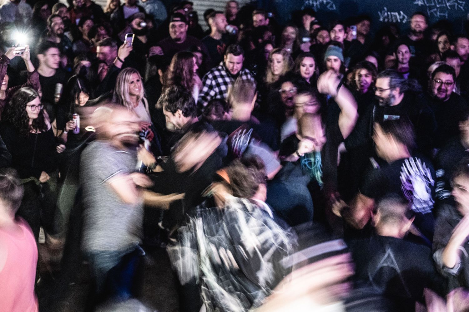 Blurred motion shot of crowd moshing and dancing at an energetic concert.