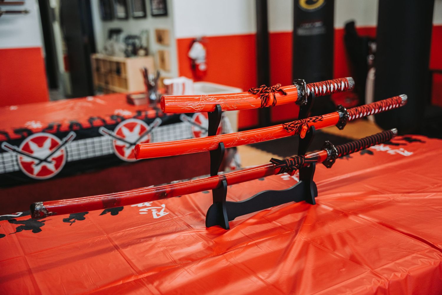 Traditional Japanese katana swords displayed on a red table with decorative wall art in the background.
