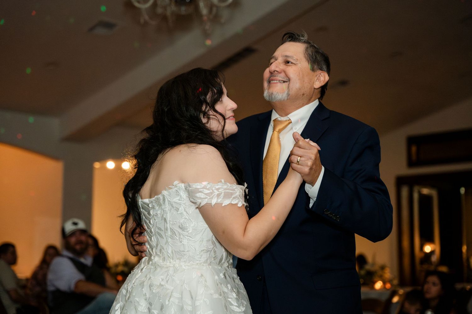 A couple shares romantic dance moments at their wedding reception in an elegantly lit ballroom.