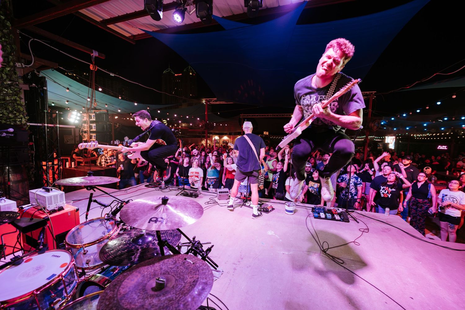 Musicians performing on stage with dramatic lighting and crowd watching from below.