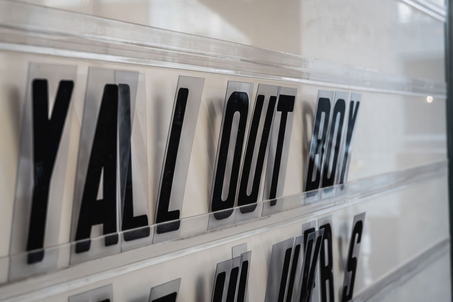Black text reading 'Y'ALL OUT BOY' displayed on white background signage.