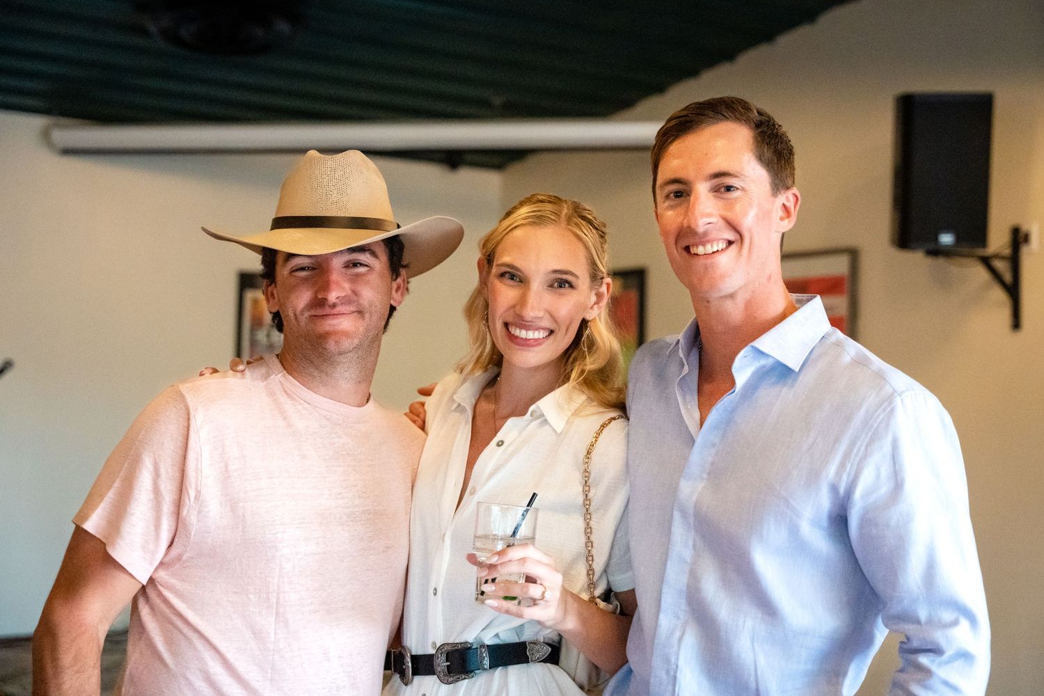 Three people pose together at an indoor event with casual summer attire.