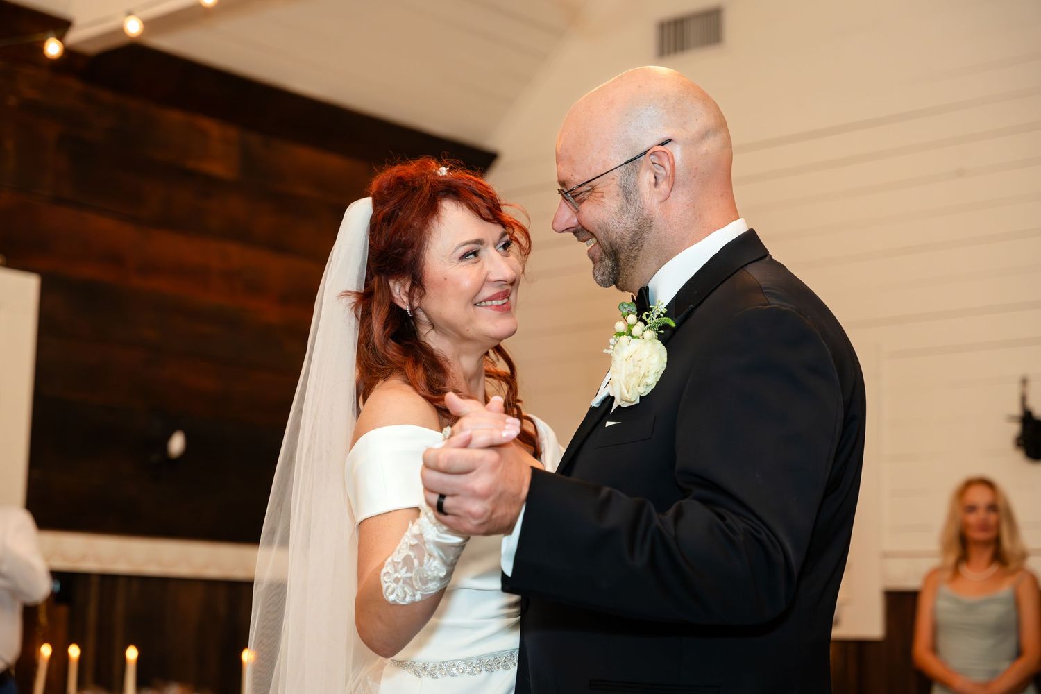 Couple sharing their first dance at a wedding reception in an indoor venue with off-white walls.