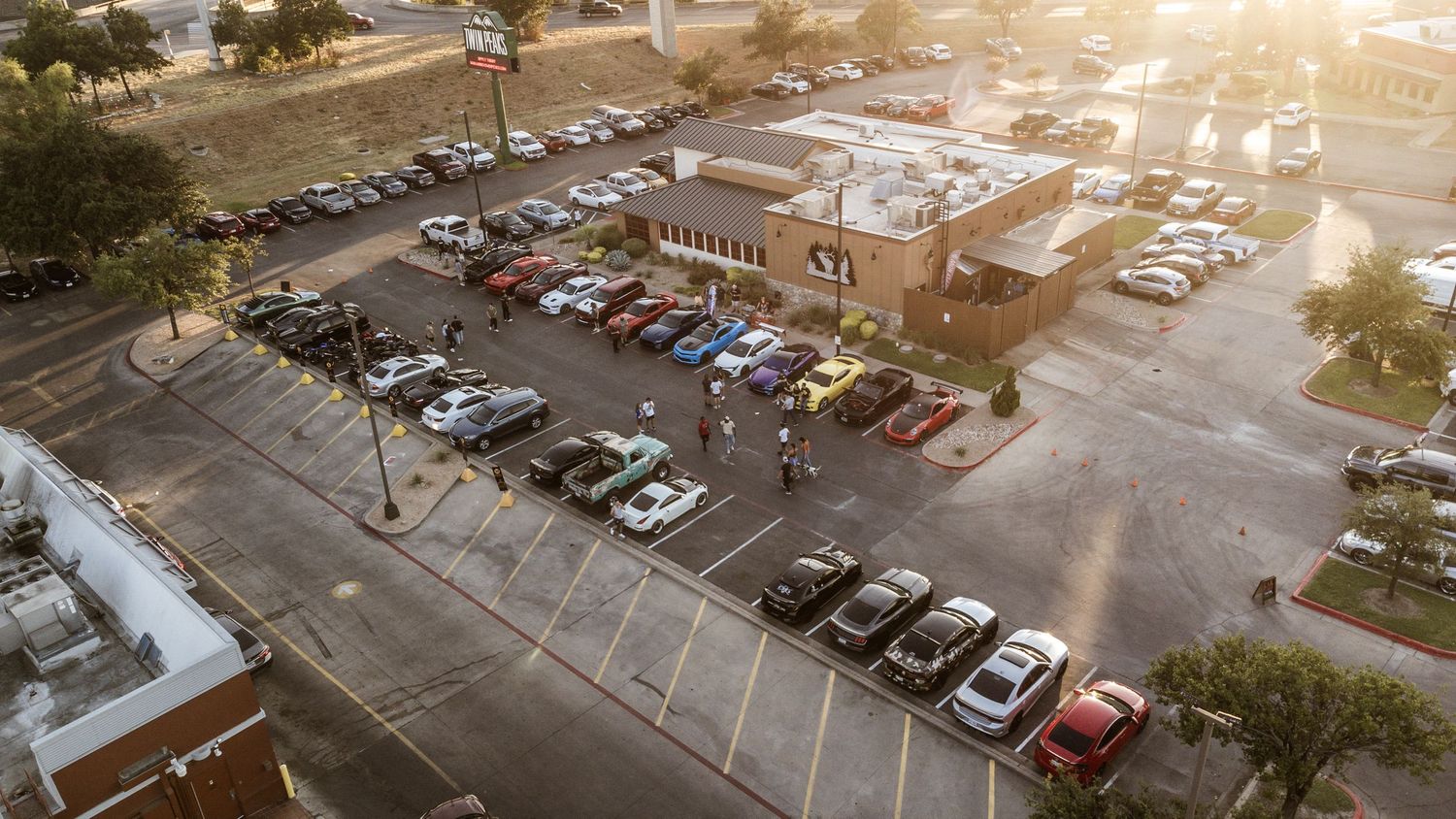Aerial view of a parking lot filled with cars at sunset.