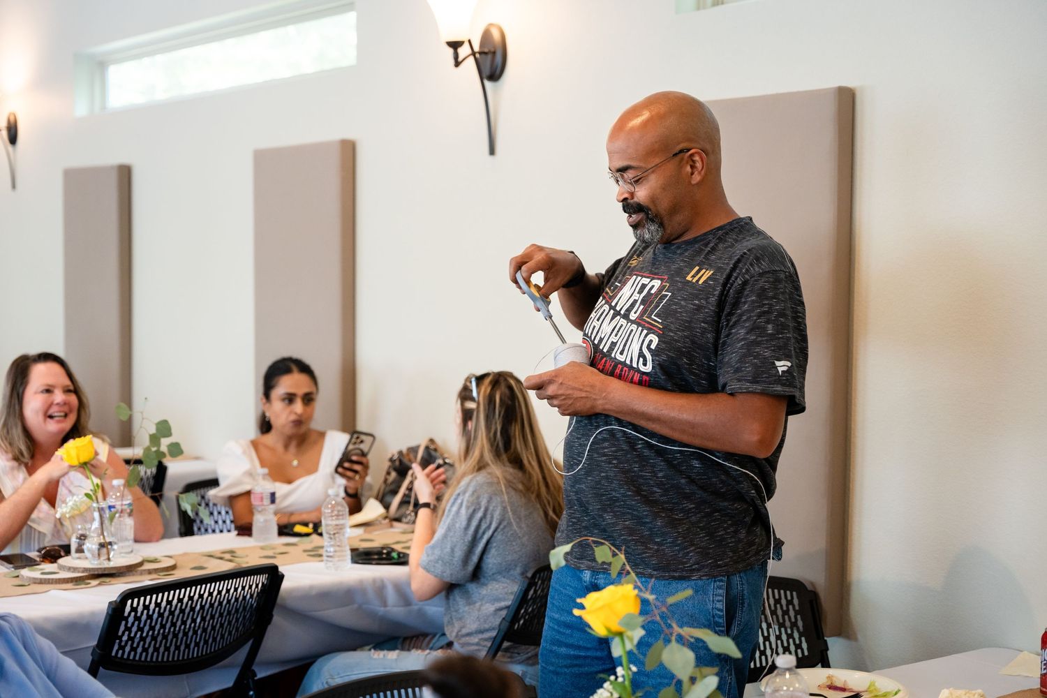 A casual indoor celebration with guests seated at decorated tables sharing conversation.