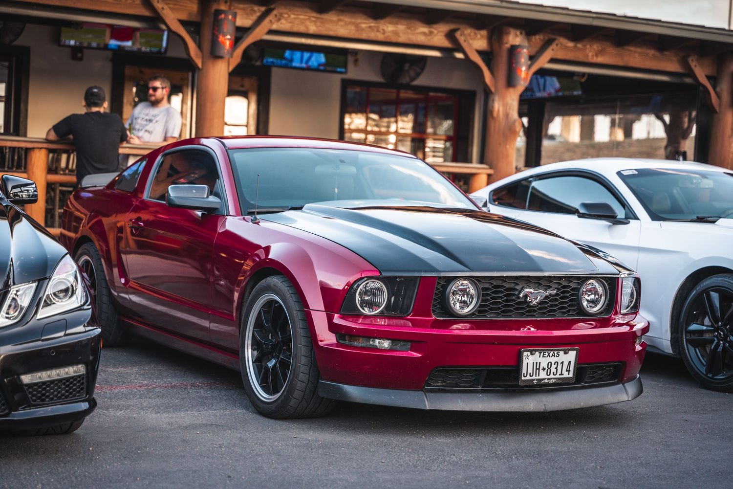 Custom burgundy Ford Mustang with black wheels and body modifications on display.