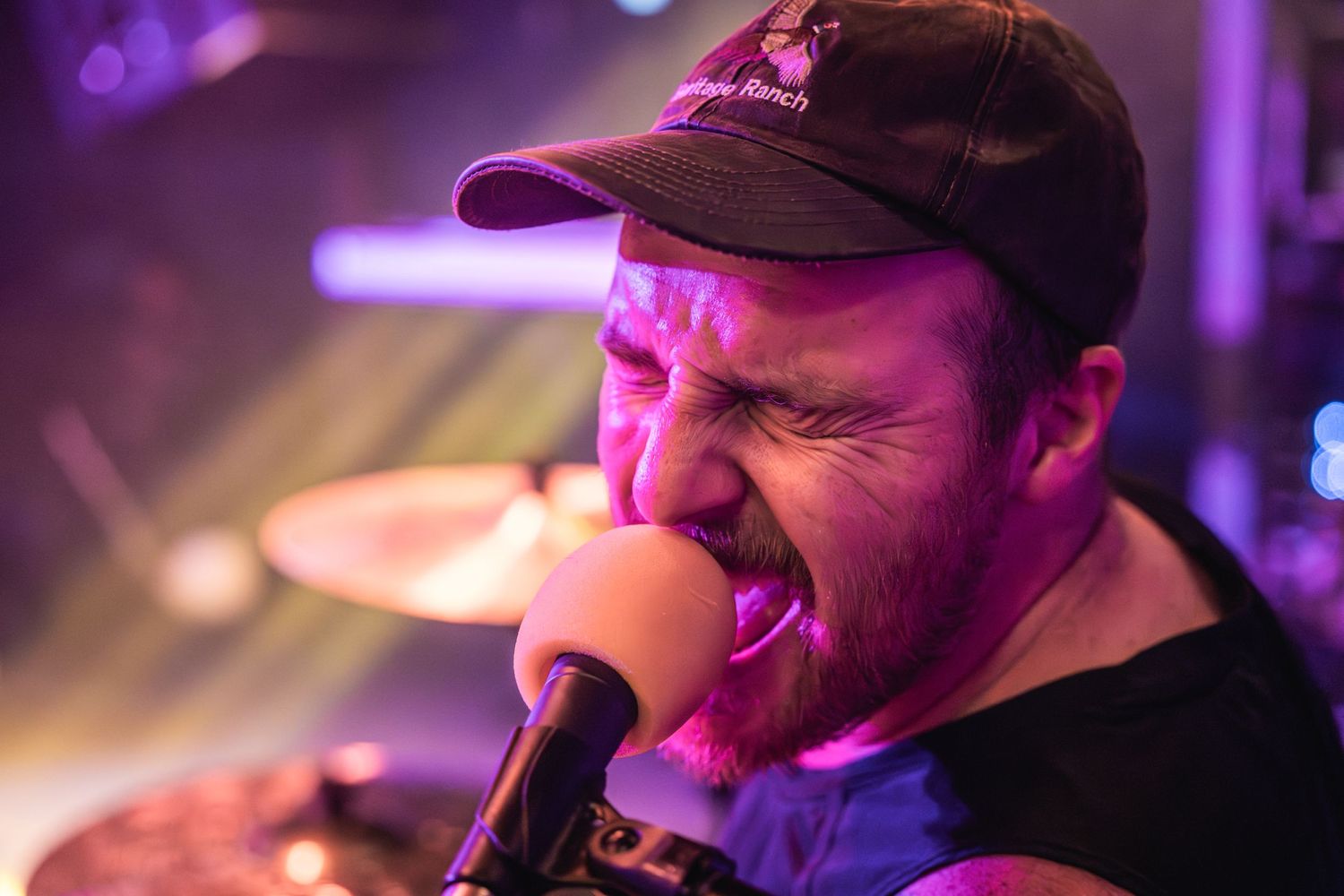 Vocalist sings passionately into microphone under purple stage lighting.