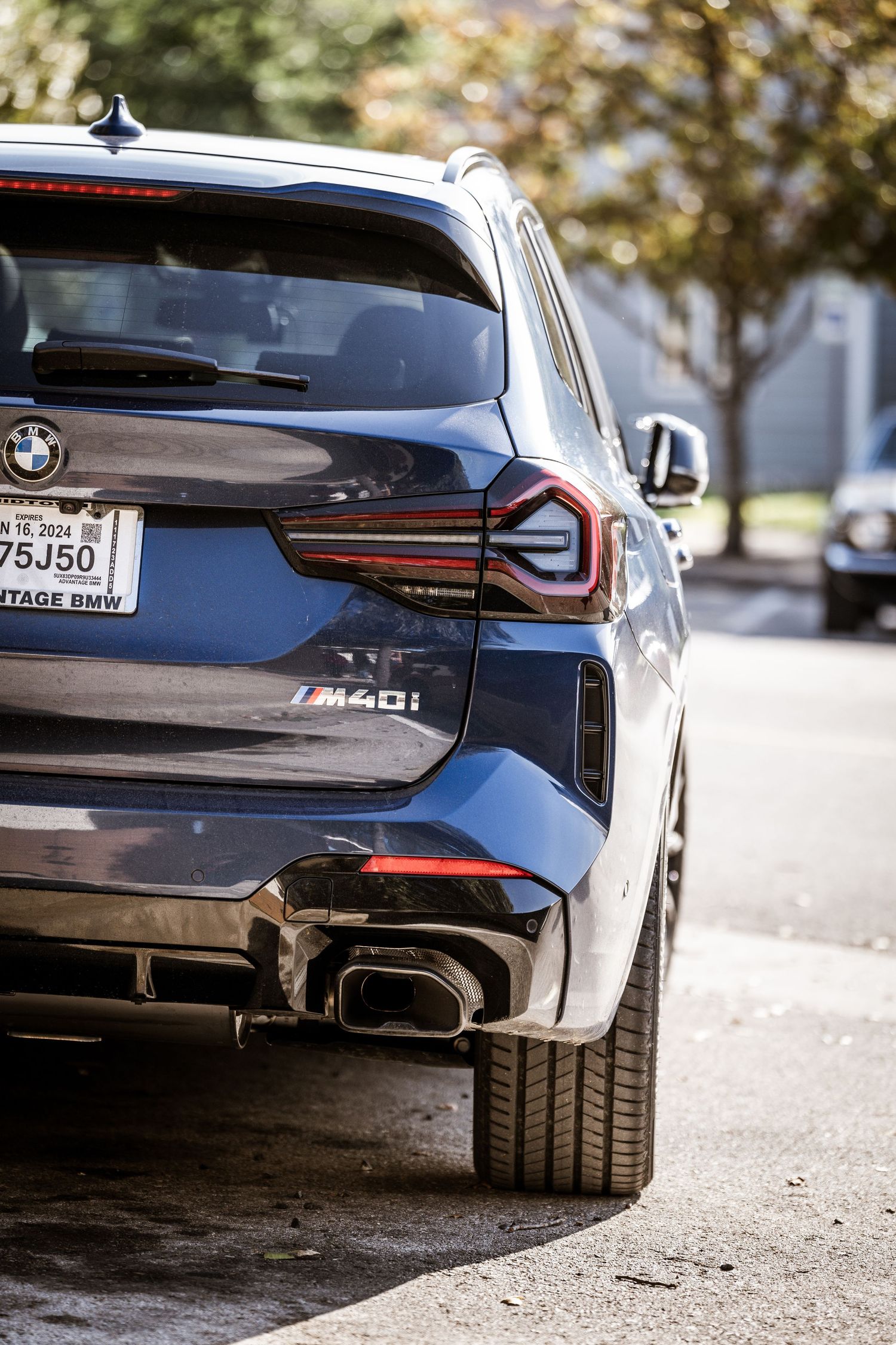 Rear quarter view of a modern BMW M40i SUV showing distinctive LED taillights and dual exhaust.