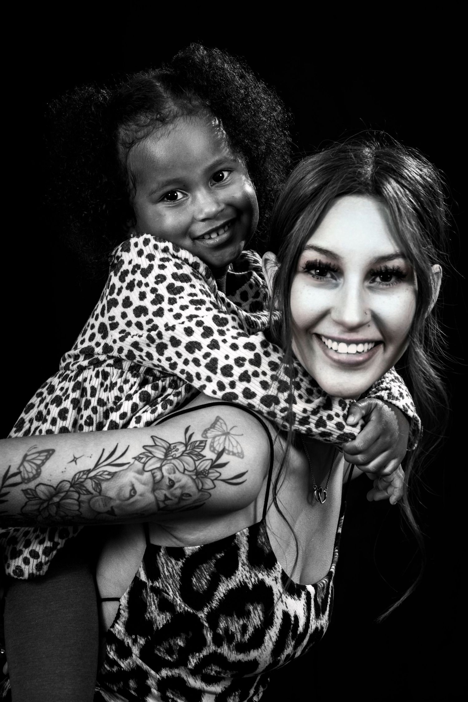 Candid black and white portrait shows piggyback ride with matching leopard print outfits.