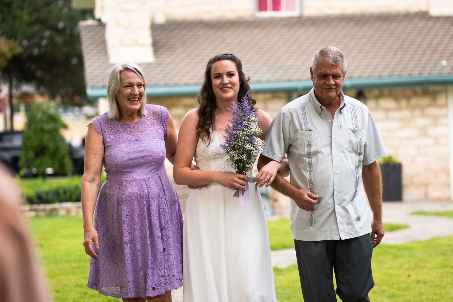 A wedding moment captured outdoors with purple dress details and floral bouquet.