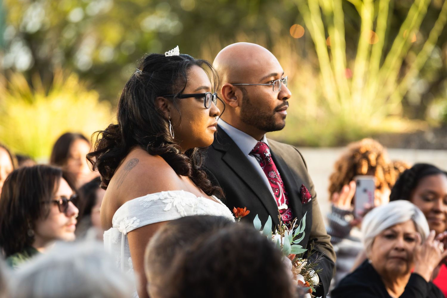 Wedding couple shares intimate moment during outdoor ceremony with guests watching.