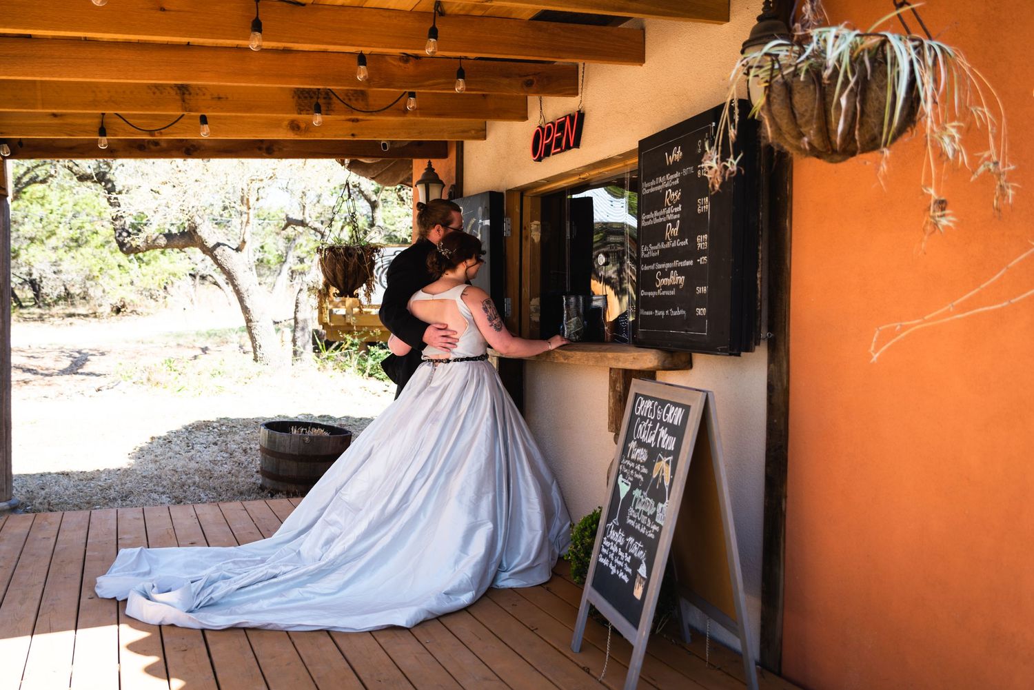A light blue wedding gown flows elegantly against a rustic wooden porch and orange wall.