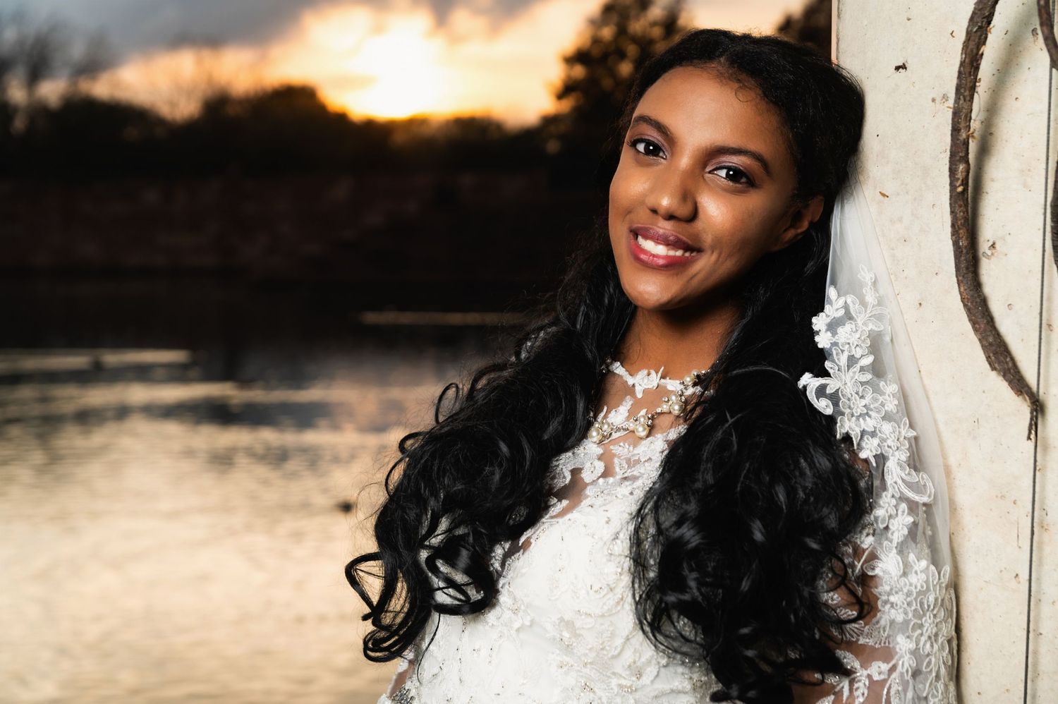 Elegant bridal portrait at sunset with lake and dramatic sky backdrop.