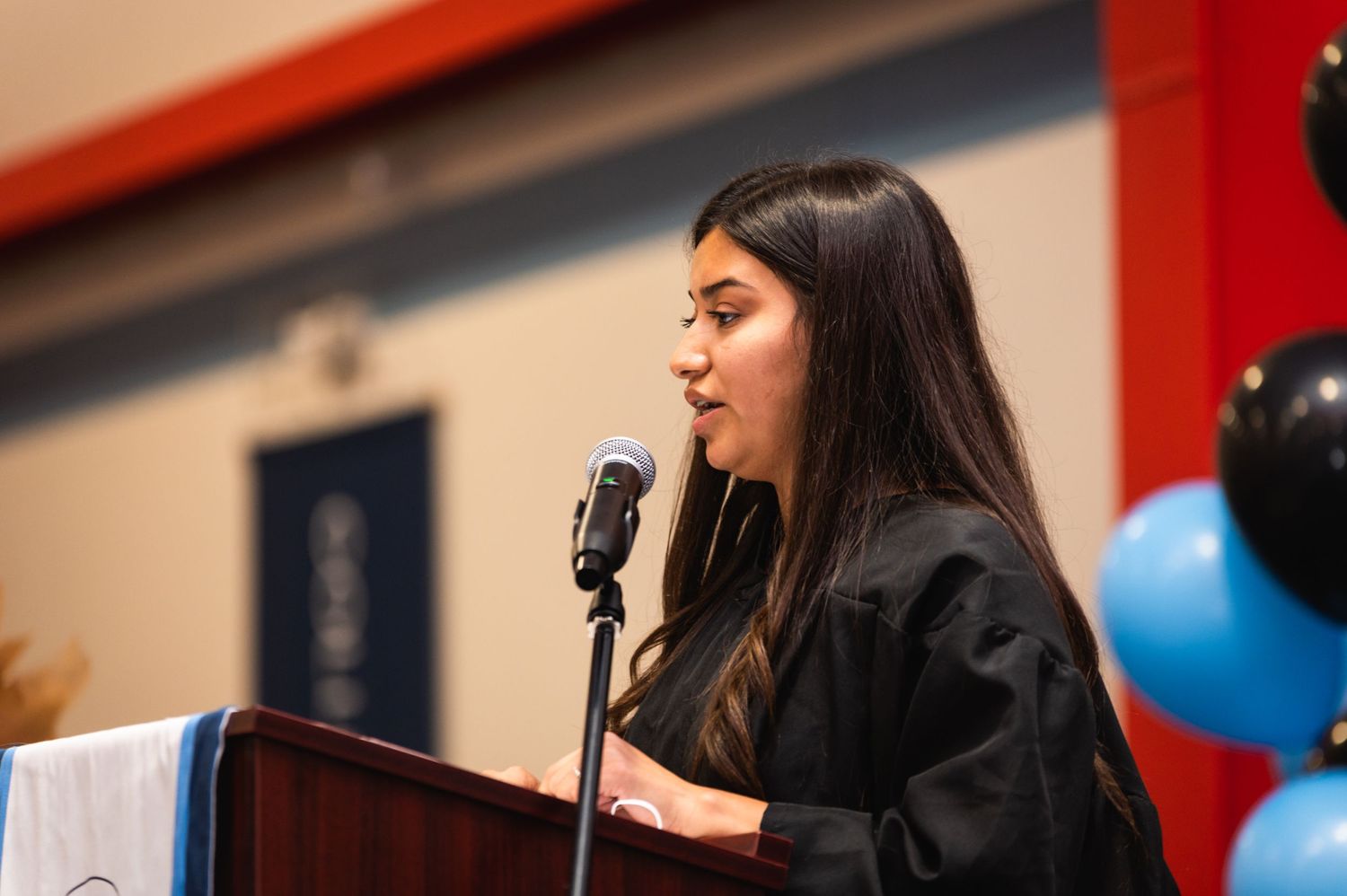 Graduate delivering speech at podium during commencement ceremony.