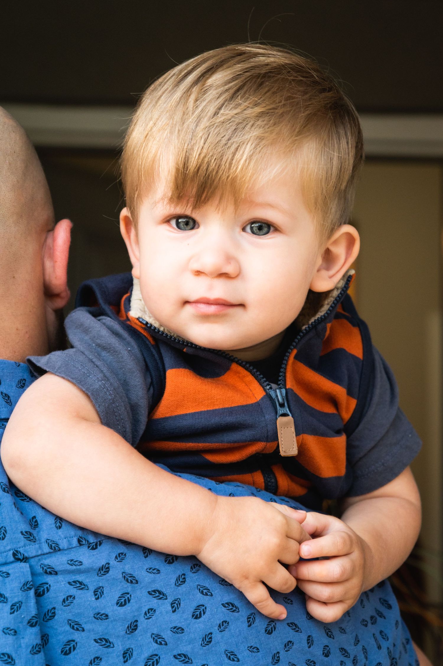 Close-up portrait of young child wearing navy and orange striped outfit.