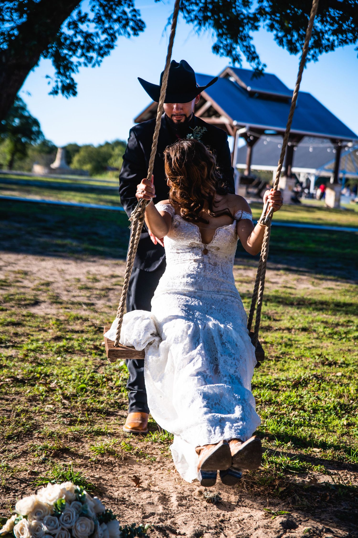 Couple enjoying romantic moment on swing during outdoor country wedding.