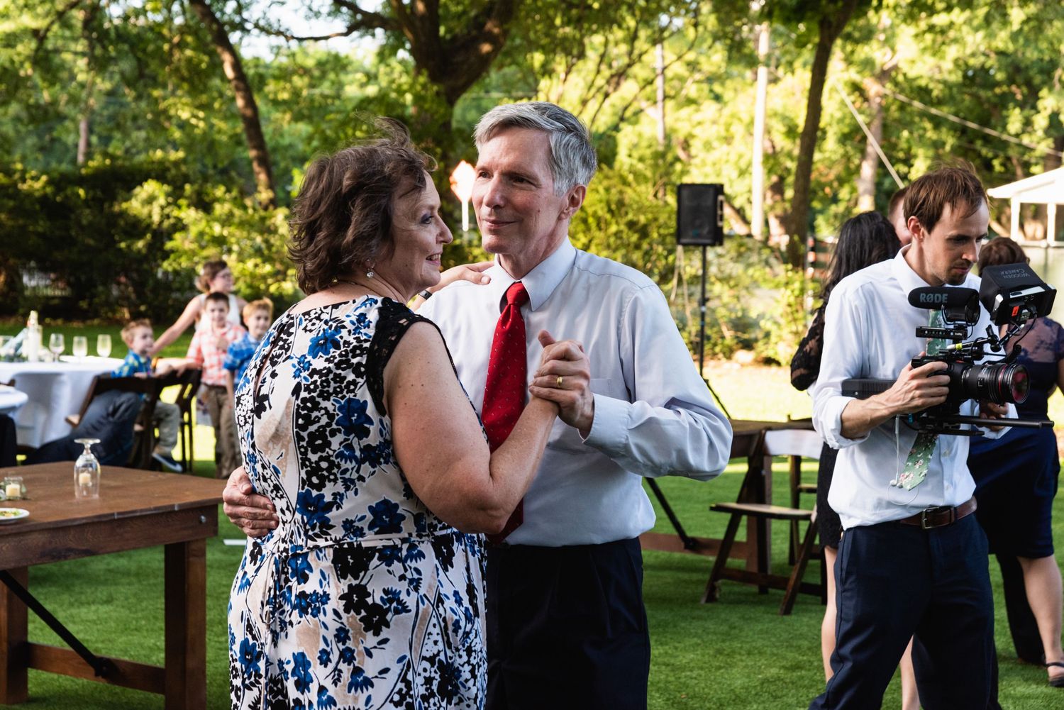 Couples dance together during an outdoor evening wedding reception on a grassy lawn.