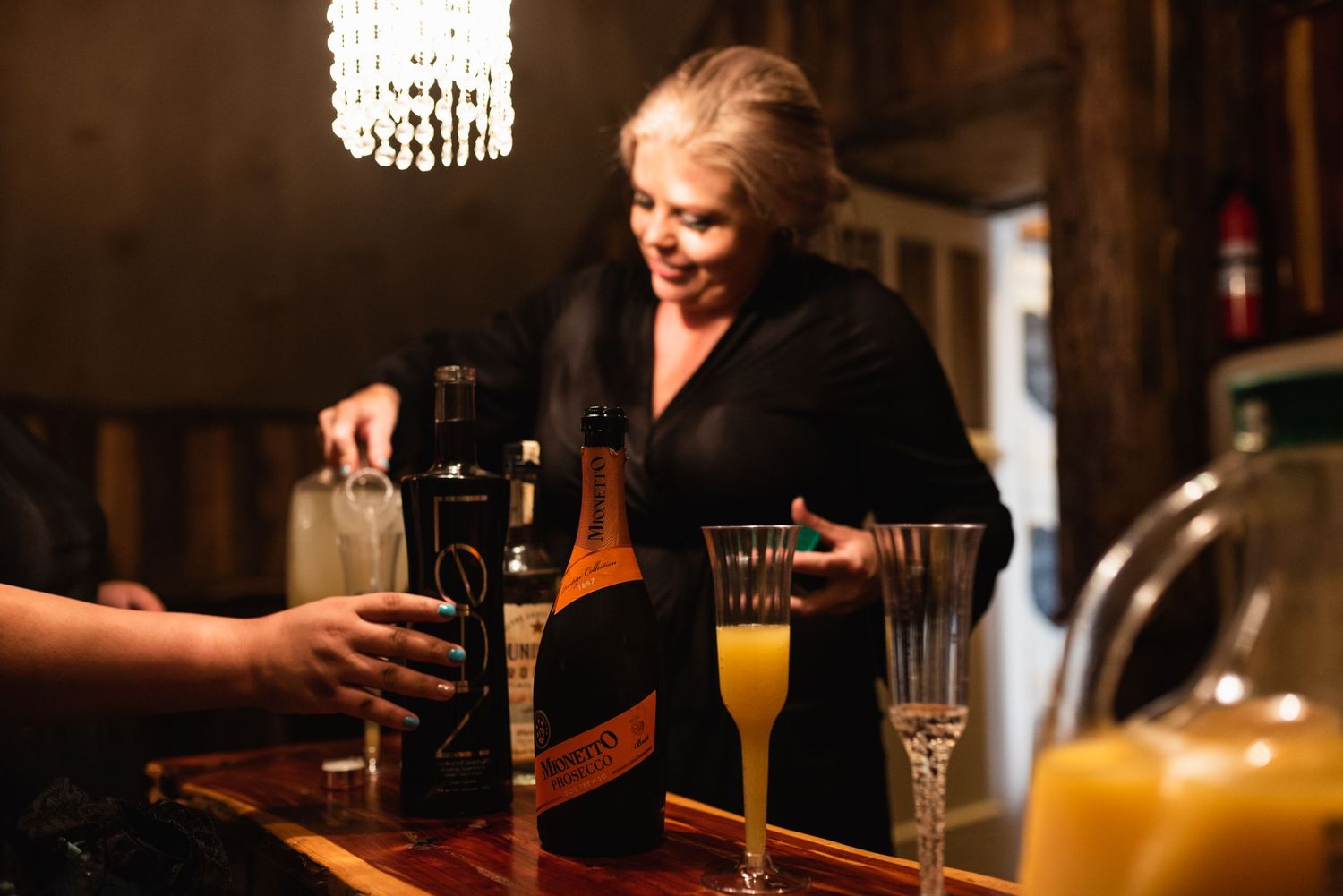 Drinks being served at a bar with mimosas and dark beverages visible.