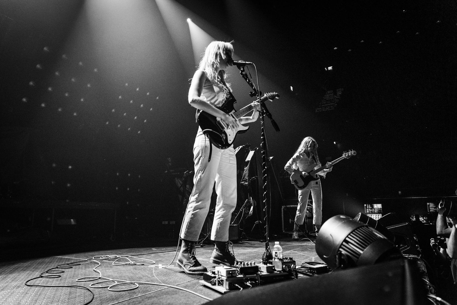 Black and white stage photo of musicians performing with dramatic concert lighting effects.