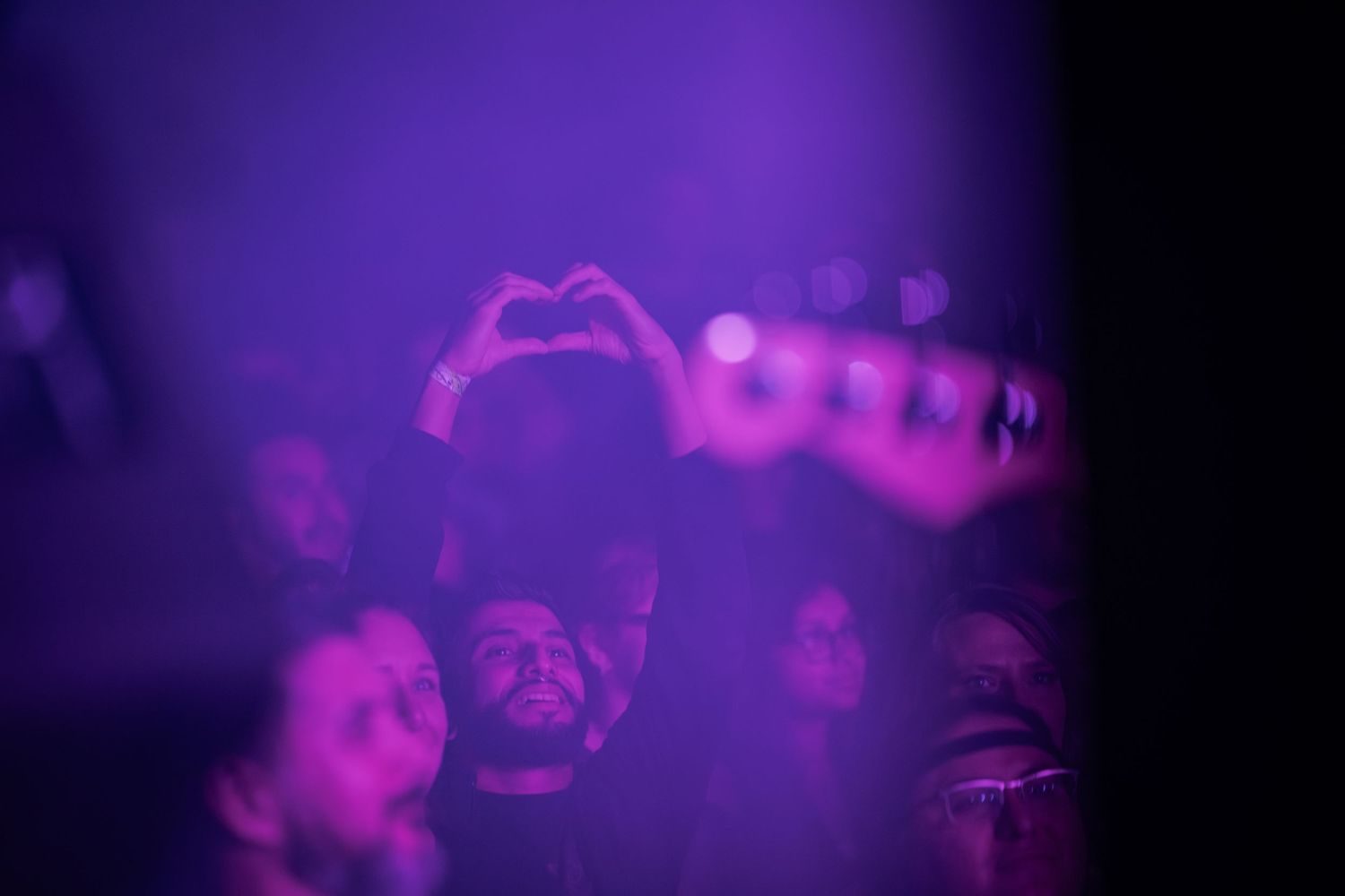 A series of dark purple and magenta concert photos showing silhouettes of performers on stage with atmospheric lighting.