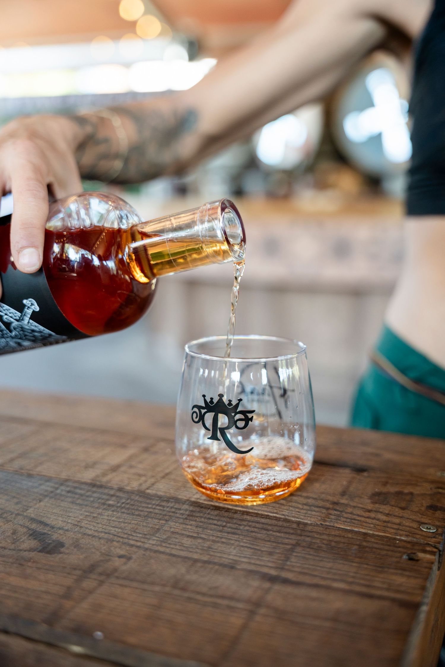 Sequence of four shots showing bourbon being poured into a glass tumbler on a rustic wooden table.