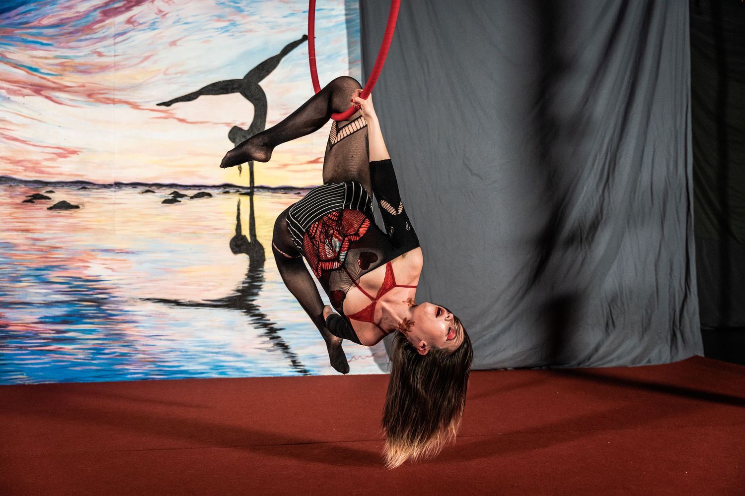 Silhouetted figures perform aerial acrobatics against a colorful backdrop in a dramatic circus performance series.