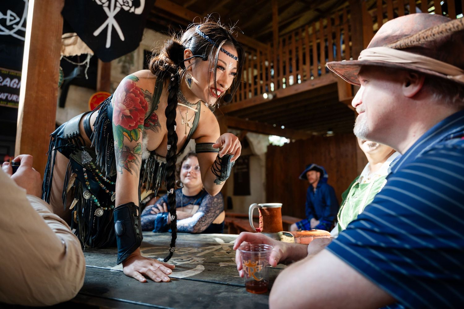 People sit at a bar counter in a dimly lit establishment while a bartender serves drinks.