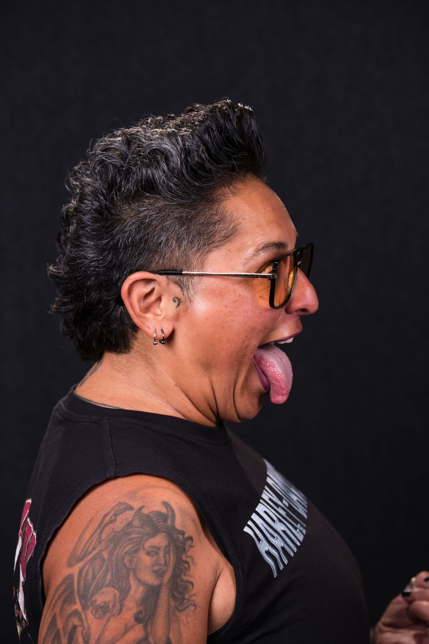 A series of photos showing a person with a large tattoo on their back making expressive faces against a dark background.