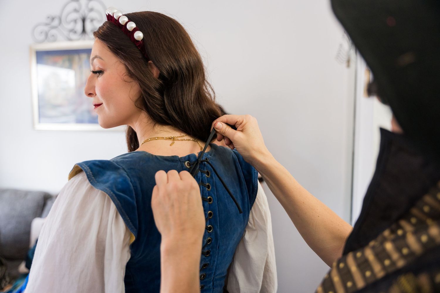 A hairstylist works on styling a client's long brown hair in a bright salon setting.