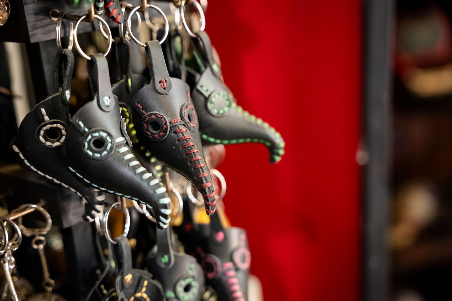 Close-up view of decorative metal keychains and trinkets hanging against a red background.
