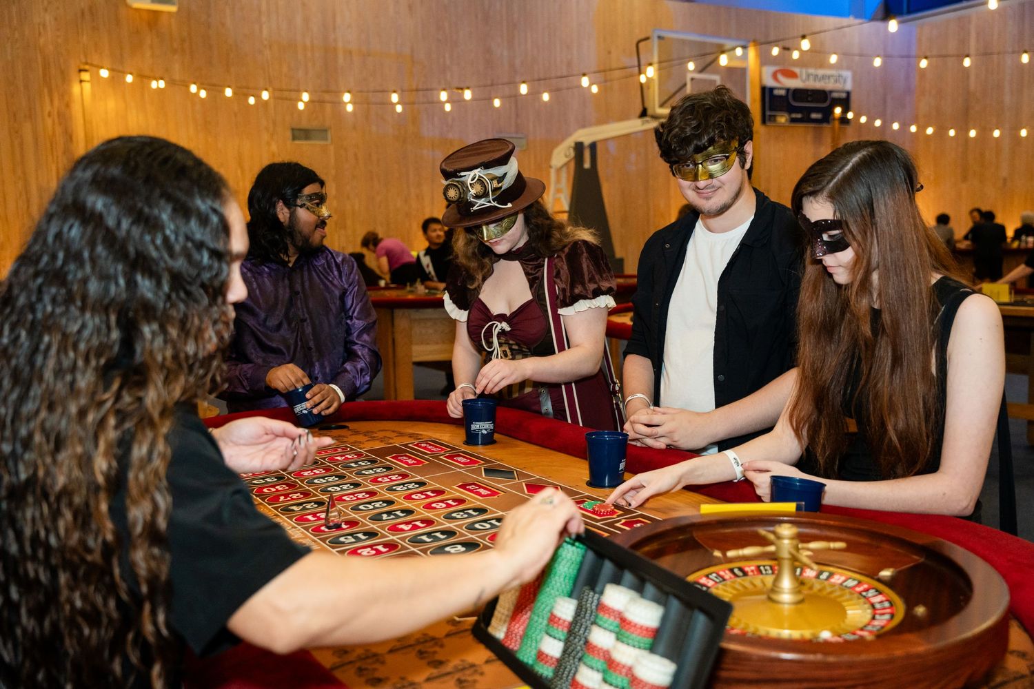 Players enjoying a roulette game at a casino-themed event with string lights.