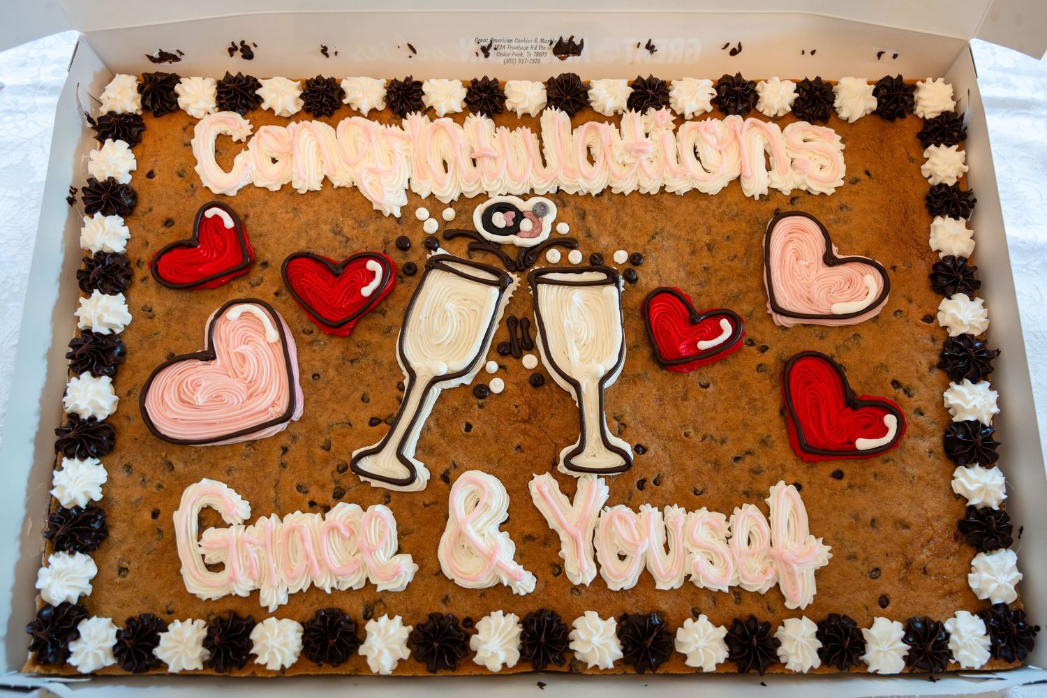 A chocolate sheet cake decorated with champagne glasses and hearts for an engagement celebration.