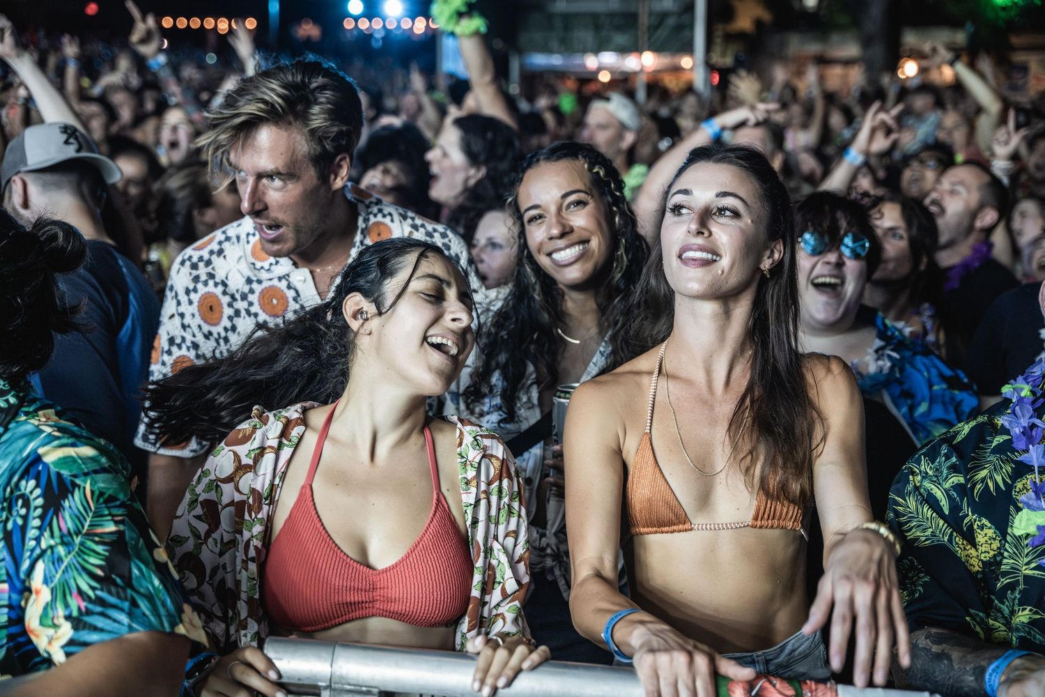 Festival attendees laugh and smile while enjoying an outdoor music performance.