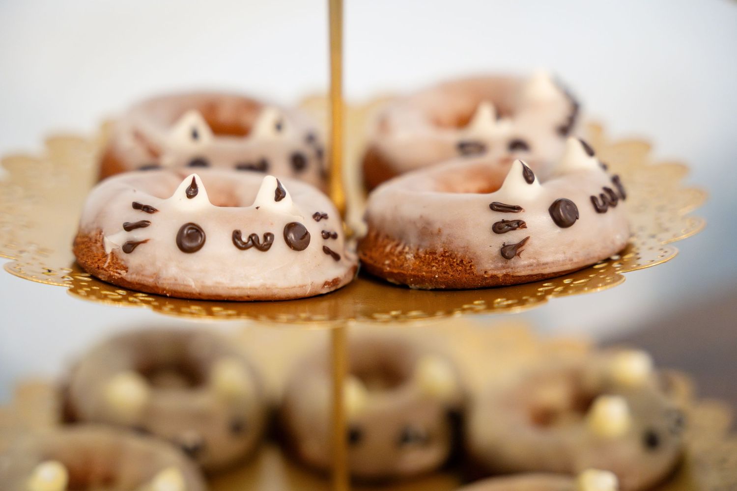 Adorable cat-shaped macarons with kawaii faces displayed on a tiered serving platter.