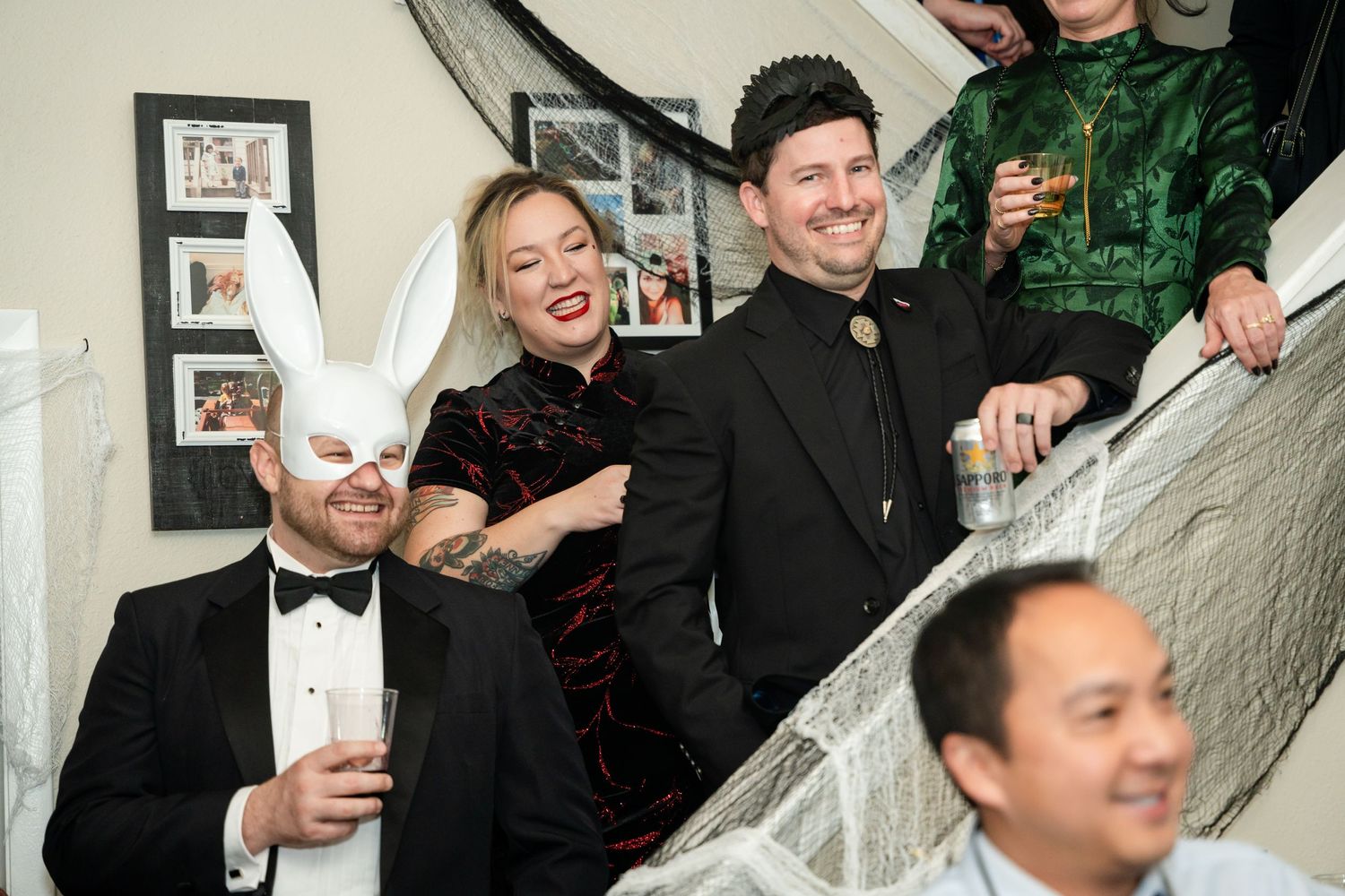 Party guests celebrate on a staircase decorated with spooky Halloween themed elements.