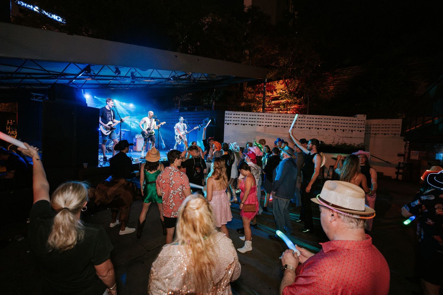 Concert crowd watching band perform on stage with blue lighting effects.