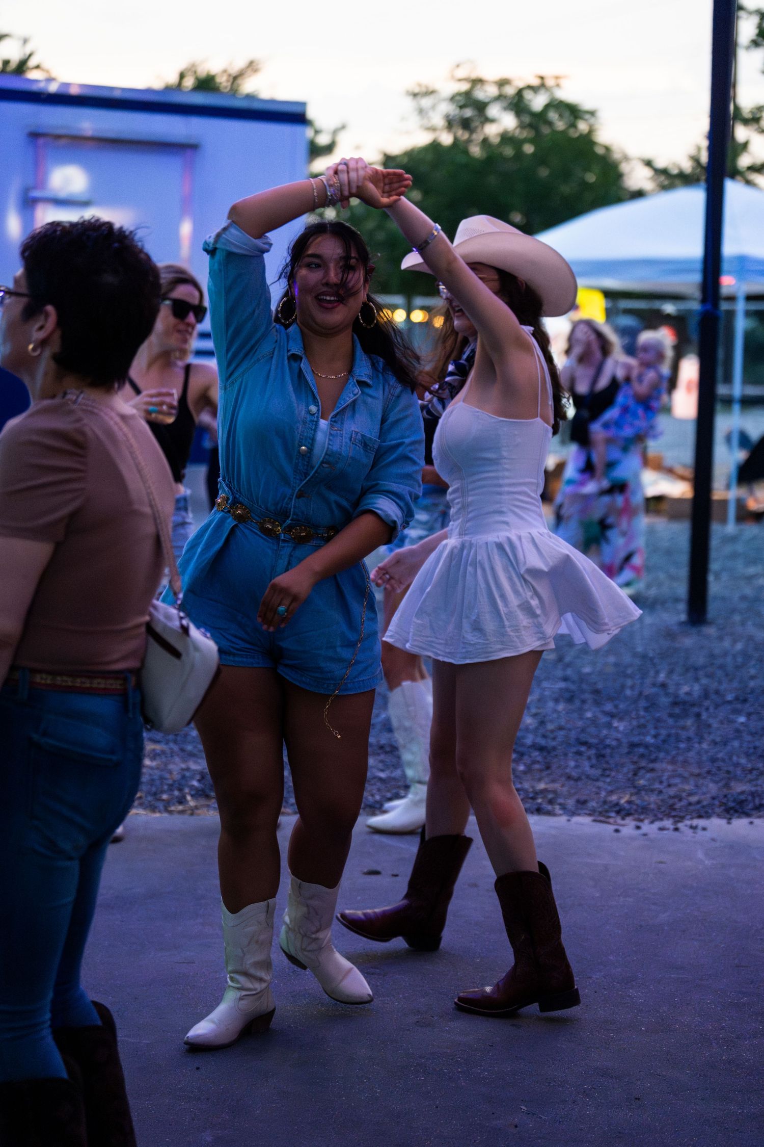A group of people dancing and having fun at a dusk gathering with one person in a blue shirt standing out.