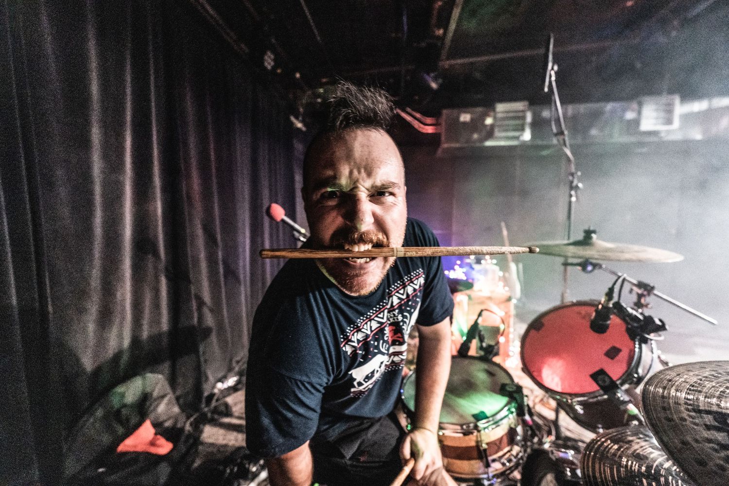 Drummer performs with energetic expression during concert set.