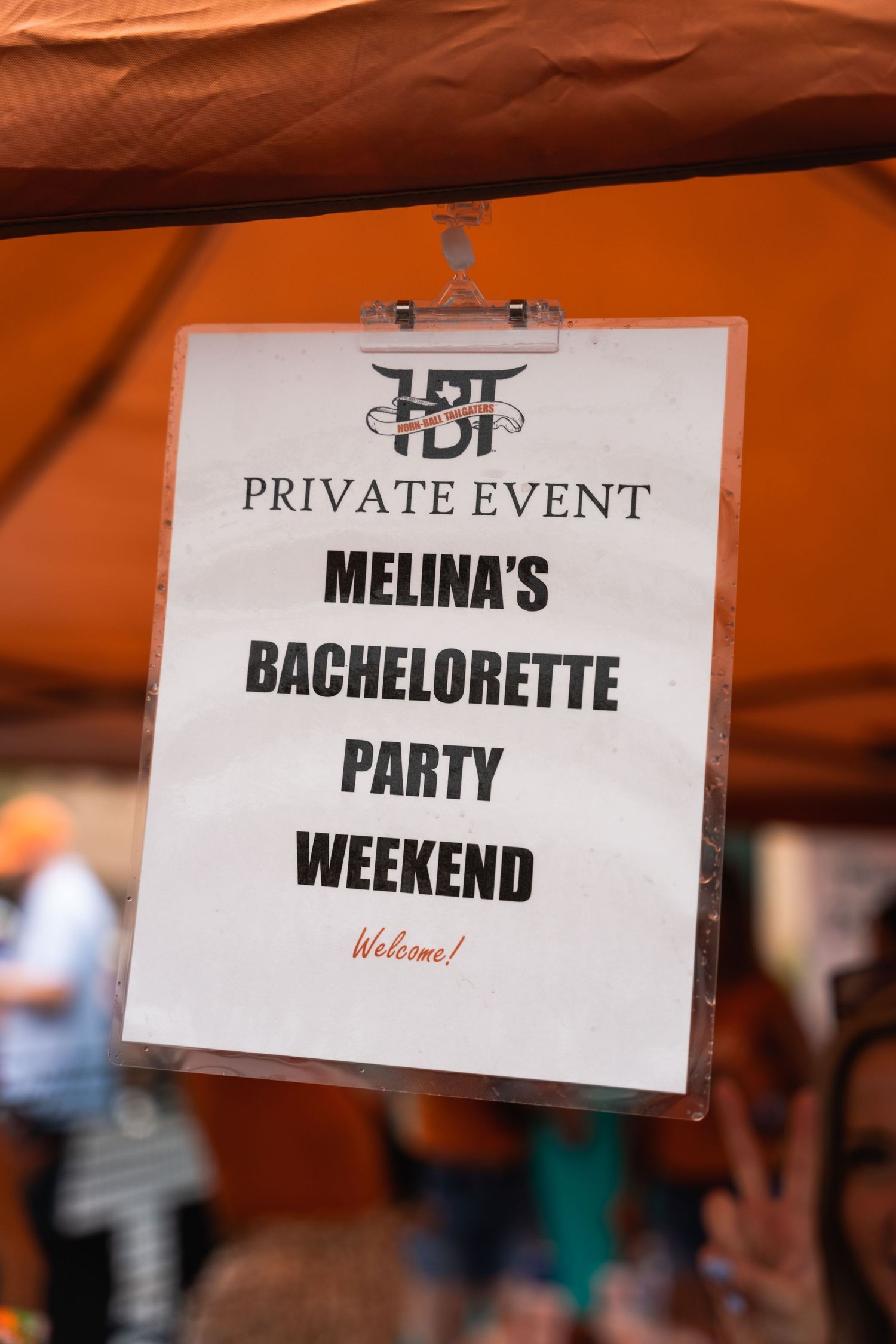 Sign for Melina's Bachelorette Party Weekend private event displayed on orange tent.